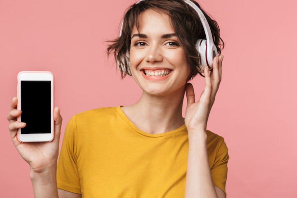 Mulher com fone de ouvido e segurando um smartphone