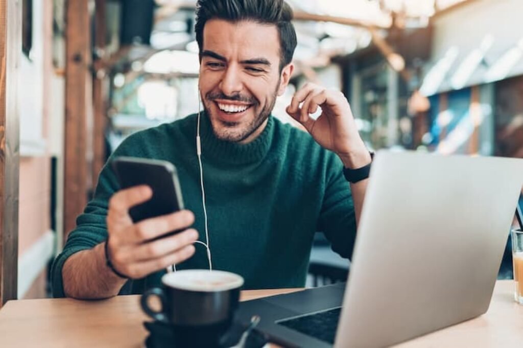 homem usando celular com computador