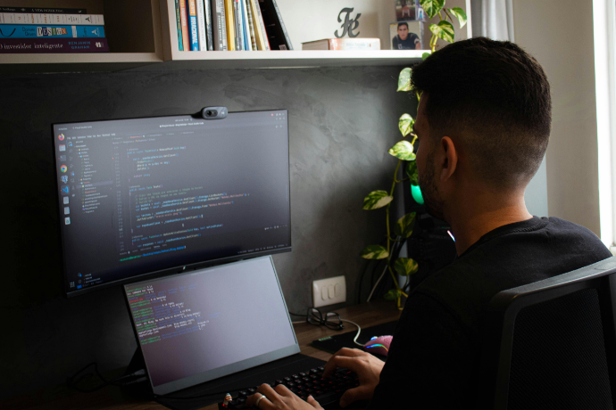 Jovem trabalhando com um monitor e uma webcam.